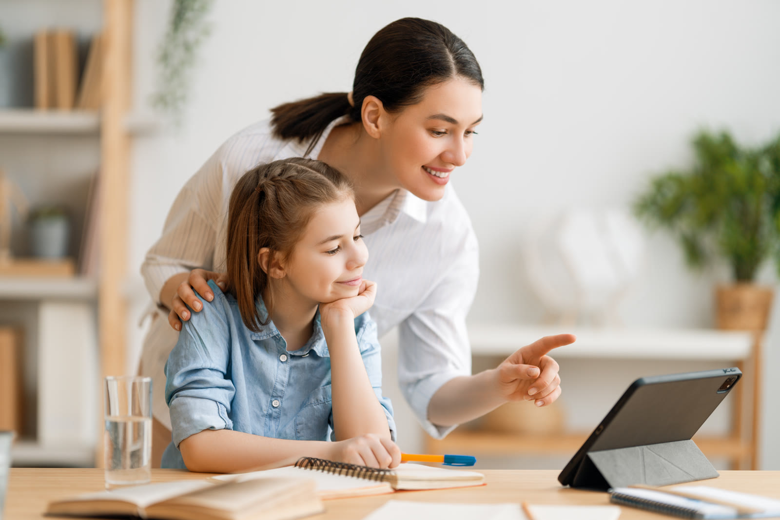 Parent calmly guiding a child through schoolwork at a table at home